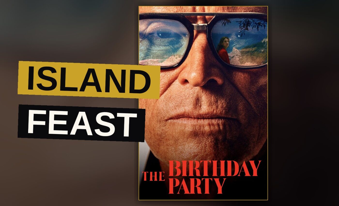 A wealthy man stands apart from his guests at a lantern-lit island feast, his face heavy with unspoken weariness.