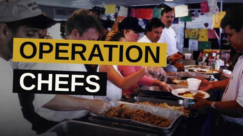 Chefs prepare meals on a barge kitchen with the Manhattan skyline behind them.