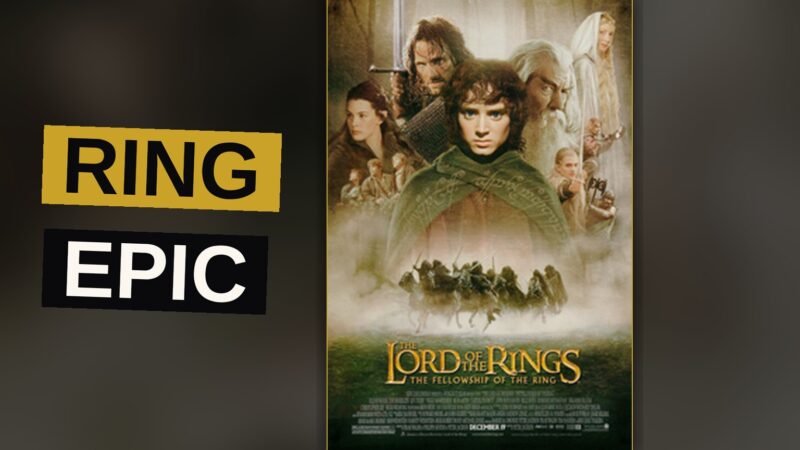 The nine members of the Fellowship walk in single file through a misty mountain pass, surrounded by towering peaks.