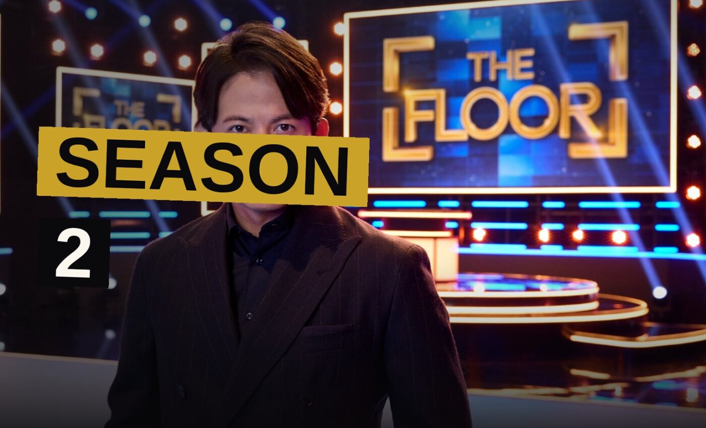 Two contestants stand on a giant illuminated grid of 100 glowing tiles in a dark TV studio.
