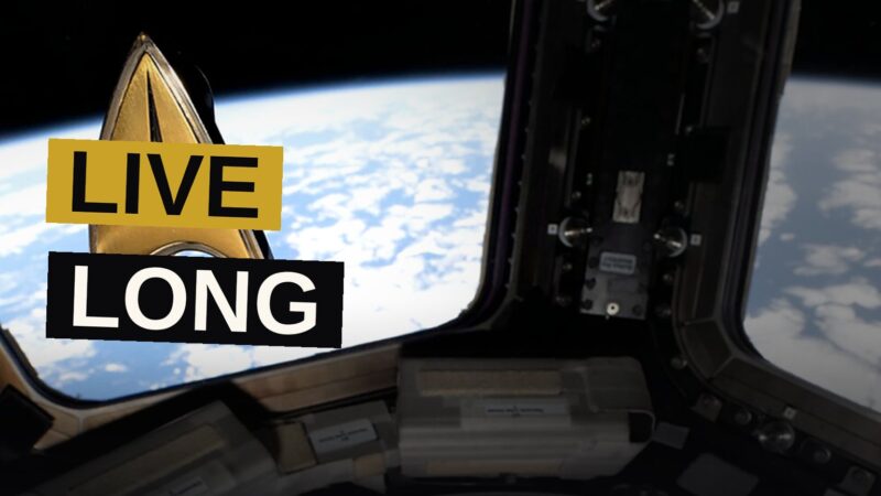 An astronaut on the station shows a hand sign while wearing a small badge, with Earth glowing beyond the window.