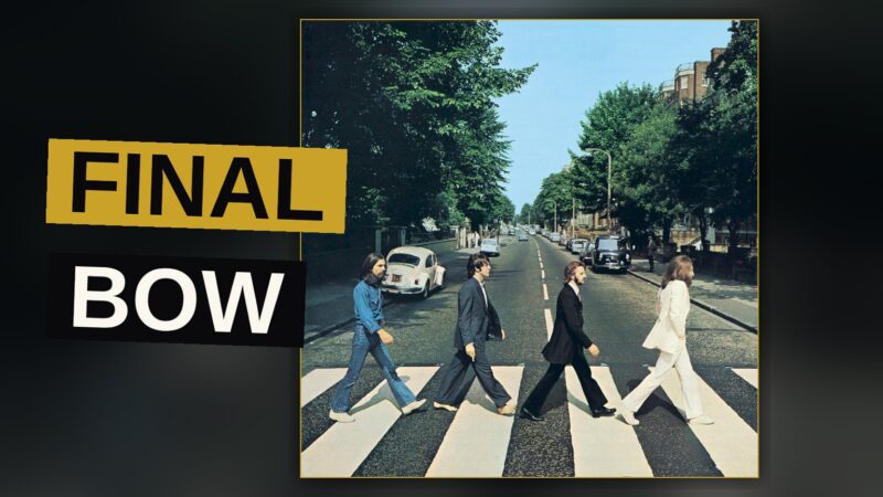 A vinyl record spins on a record player, the Abbey Road album cover leaning beside it in warm light.