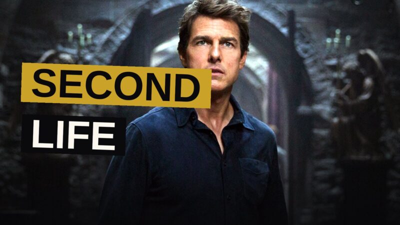 Tom Cruise stands in a dark Egyptian tomb lit by green light, with a mummy's shadow cast behind him.