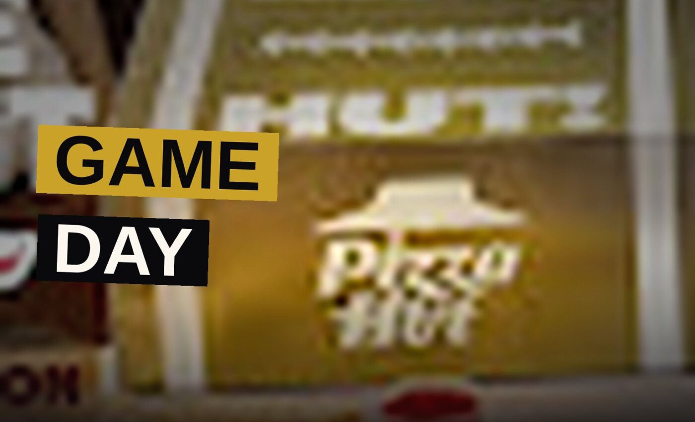 A football-themed Pizza Hut box with pull-out drawers open, showing two pizzas, breadsticks, and cinnamon sticks.