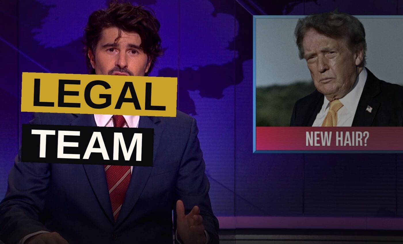 Two hosts deliver a deadpan joke on stage during a satirical comedy show.