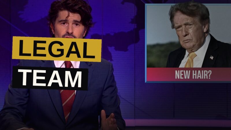 Two hosts deliver a deadpan joke on stage during a satirical comedy show.