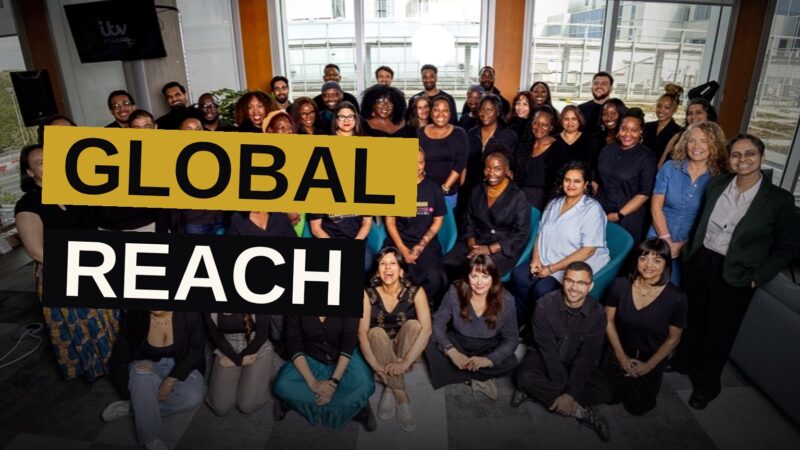 A diverse group of television industry professionals collaborating in a modern conference room with global imagery on screens.