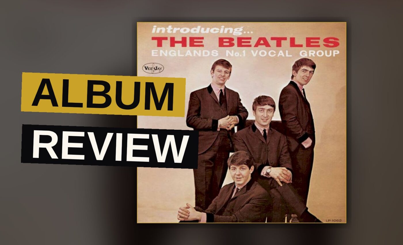 A vintage record player with the Beatles' debut album cover beside it in warm light.