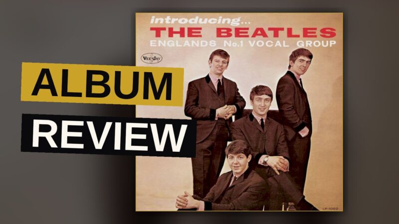 A vintage record player with the Beatles' debut album cover beside it in warm light.