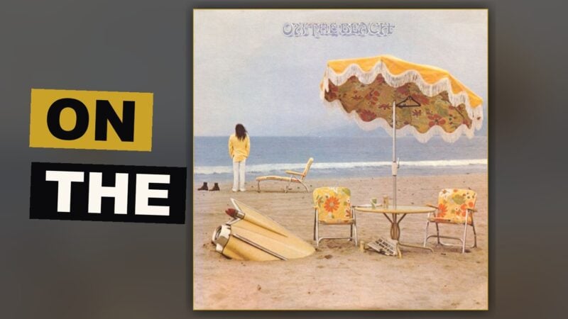 A solitary man sits upon a desolate beach, a buried automobile beside him, beneath a sky heavy with despair.