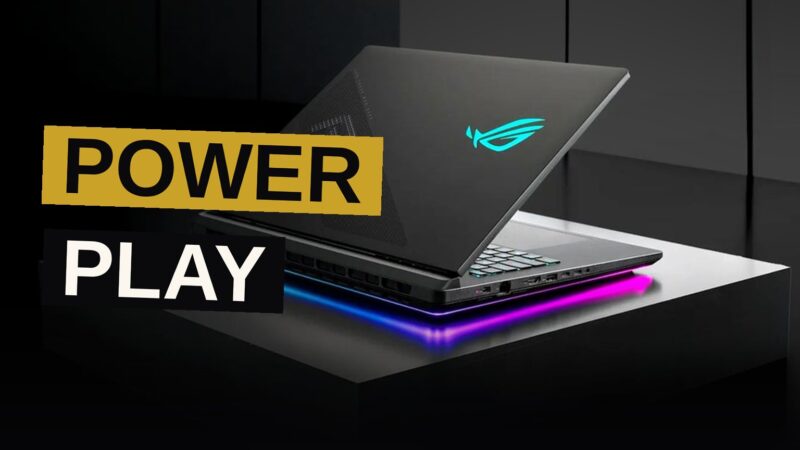 A high-end ASUS ROG gaming laptop with an illuminated keyboard and a vibrant 4K display on a dark desk.