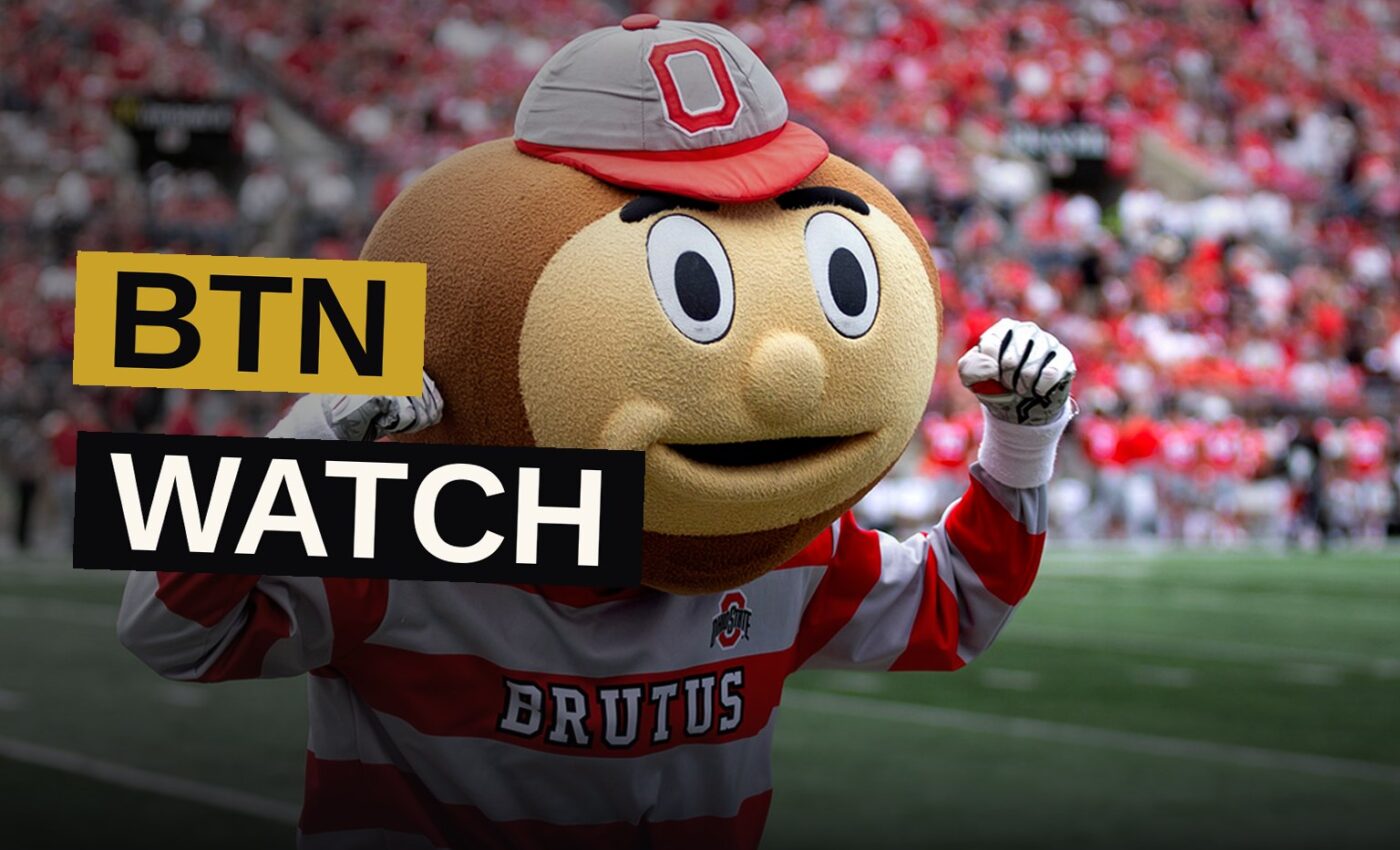 A smartphone displays a live broadcast of a college football game beneath a glowing stadium scoreboard.